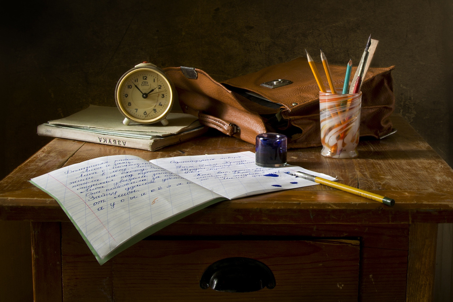 Schreibtisch mit aufgeschlagenem Heft und Stiften